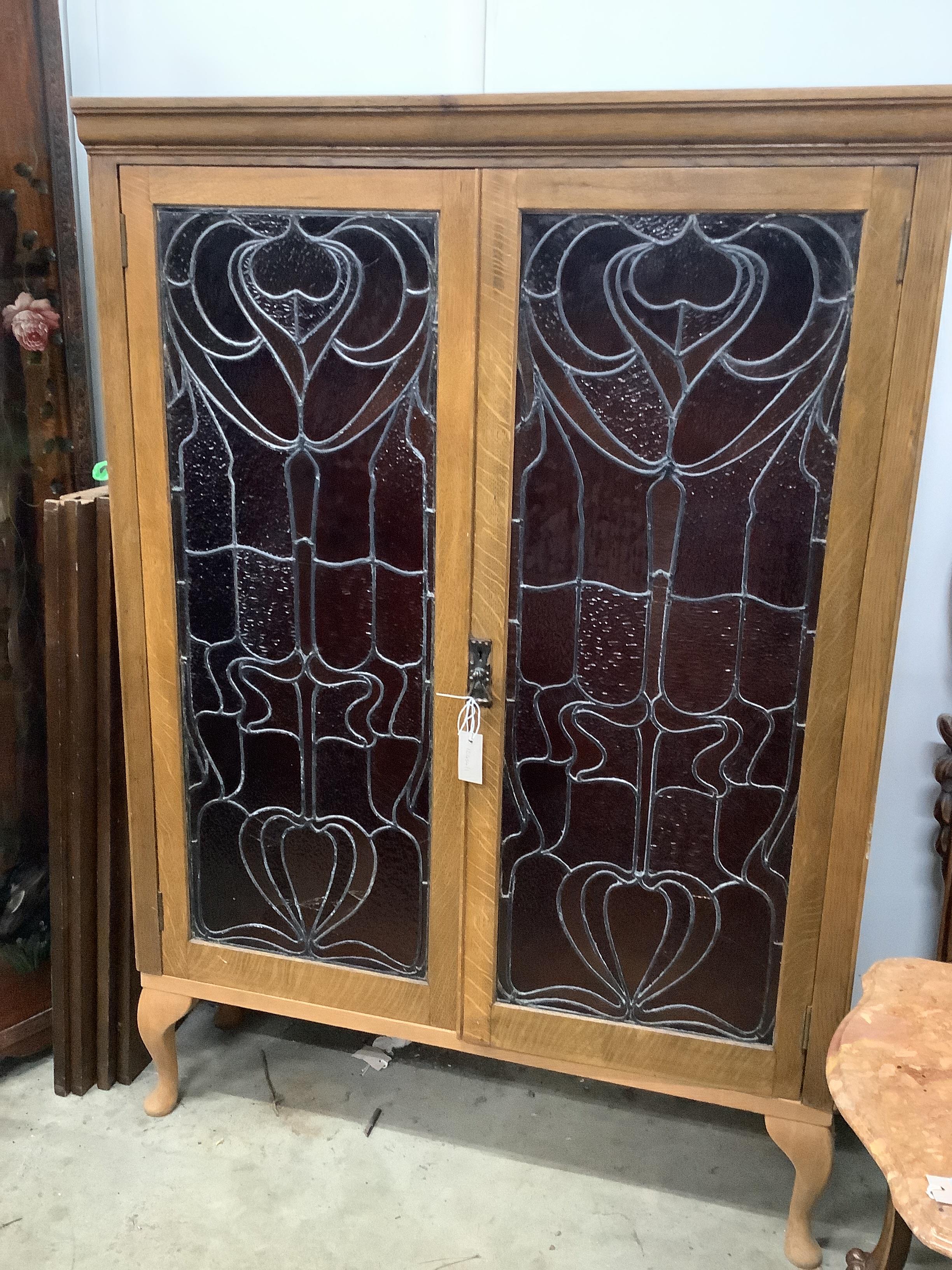 A pair of Art Nouveau stained glass panels, now as an oak bookcase, width 104cm, depth 29cm, height 150cm